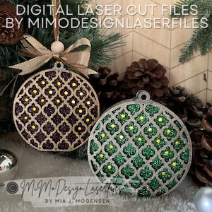 Può includere: Due decorazioni natalizie in legno tagliate al laser con un motivo geometrico. La decorazione a sinistra è viola con glitter dorati e la decorazione a destra è verde con glitter argentati. Entrambe le decorazioni hanno piccoli cerchi dorati al centro di ogni forma geometrica.