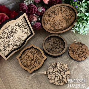 May include: Five wooden coasters with a floral design. The coasters are all different shapes and sizes, and they are all made of a light brown wood. The design is a black and white floral pattern. The coasters are perfect for adding a touch of elegance to any home.