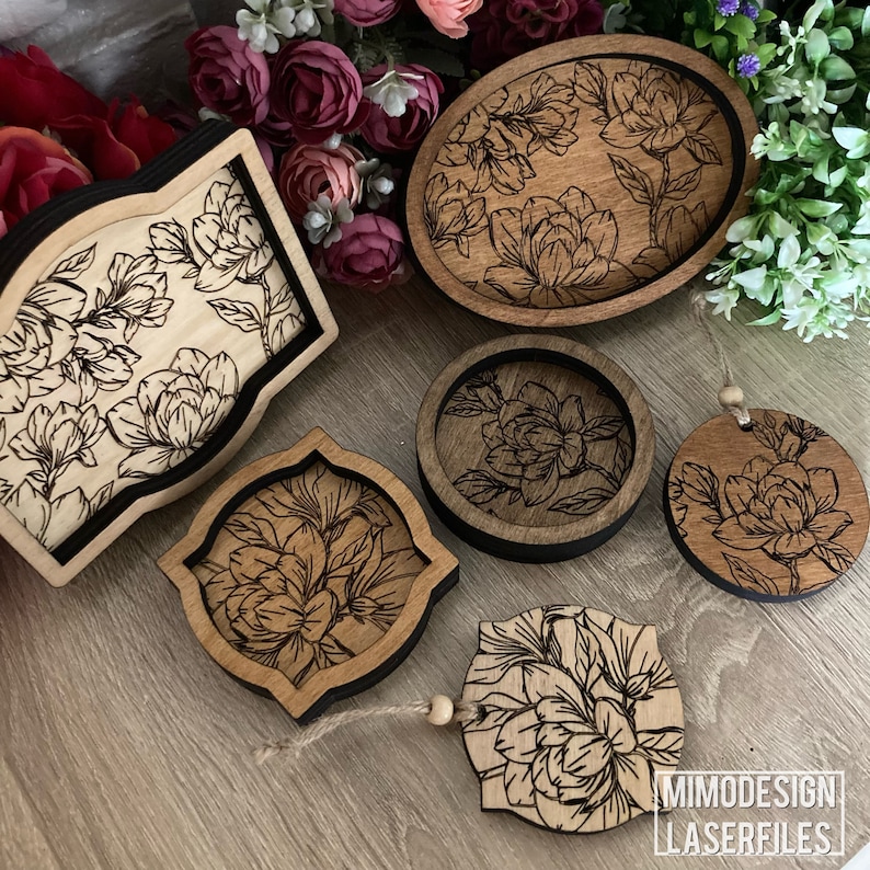 May include: Five wooden coasters with a floral design. The coasters are all different shapes and sizes, and they are all made of a light brown wood. The design is a black and white floral pattern. The coasters are perfect for adding a touch of elegance to any home.