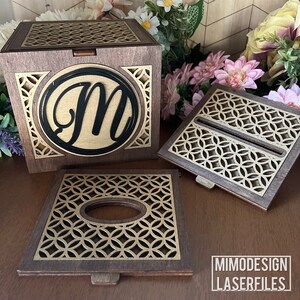 Può includere: Una scatola di legno con un design tagliato al laser e un'iniziale personalizzata "M" sul davanti. La scatola è in legno scuro con un design dorato. La scatola è aperta e il coperchio è appoggiato accanto. Ci sono altri due pezzi di legno con lo stesso design tagliato al laser. I pezzi sono per un porta fazzoletti.