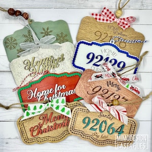 May include: A set of six wooden Christmas ornaments with various designs and text, including "Home for Christmas", "Merry Christmas", "Home is where", "Home for Christmas", "Santa Stop Here", and "Merry Christmas". Each ornament features a different color scheme and decorative elements.