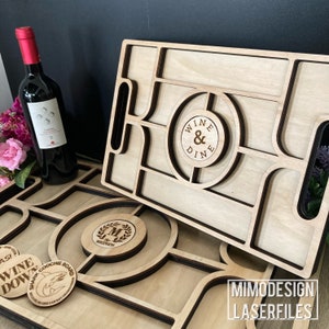 K&ouml;nnte beinhalten: Zwei Holztabletts mit Ausschnitten f&uuml;r Gl&auml;ser und Snacks. Das obere Tablett hat einen Kreis mit dem Text "Wine & Dine" und das untere Tablett hat einen Kreis mit dem Text "Shark Coochie Board".