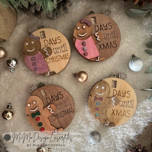 Può includere: Quattro ornamenti di Natale in legno a forma di pan di zenzero. Ogni ornamento ha un conto alla rovescia a lembo con numeri e il testo "Days until Christmas" o "Days until Xmas".