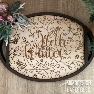 May include: A wooden oval serving tray with a dark brown rim and a light wood center. The center is engraved with a floral design and the words "Hello Winter".