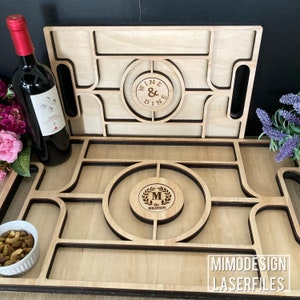 K&ouml;nnte beinhalten: Ein Serviertablett aus Holz mit einem Laser-Schnitt-Design. Das Tablett hat ein Fach f&uuml;r eine Weinflasche, eine kleine Sch&uuml;ssel und ein gr&ouml;&szlig;eres Fach f&uuml;r Snacks. Das Tablett ist mit den Worten "Wine & Dine" und "M. & Mrs. Mogensen" graviert.