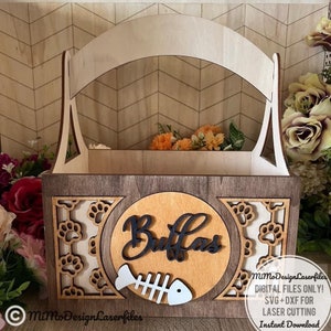 Può includere: Una scatola di legno con manico, progettata per contenere dolcetti per cani o altri accessori per animali domestici. La scatola presenta un design a taglio con impronte di zampe e la parola "Buffas" sul davanti. Il testo "MiMo Design Laserfiles FILE DIGITALI SOLO! SVG+DXF PER TAGLIO LASER Download immediato" è anche visibile.
