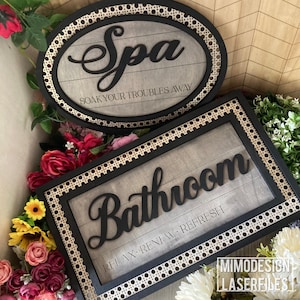 May include: Two wooden signs with black lettering and frames. One sign reads "Spa" with "SOAK YOUR TROUBLES AWAY" below, and the other says "Bathroom" with "RELAX • RENEW • REFRESH". Both have a decorative border.