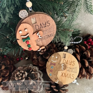 Può includere: Due ornamenti di Natale in legno a forma di pan di zenzero per il conto alla rovescia. Gli ornamenti sono decorati con dettagli rossi, verdi e bianchi. L'ornamento superiore dice "Days until Christmas" e l'ornamento inferiore dice "25 Days until Xmas".