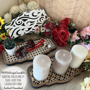May include: A wooden tray with a decorative cut-out design, featuring three candles, a pair of sunglasses, a potted succulent, and a key chain. The tray is on a light brown surface with a chevron pattern.
