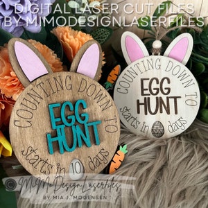 May include: Two wooden signs with bunny ears, counting down to an egg hunt. The signs are brown with white text and a teal egg hunt graphic. The text reads "Counting down to Egg Hunt starts in 10 days".