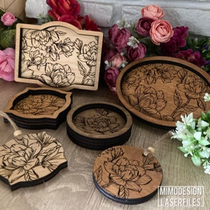 May include: A set of five wooden coasters with a floral design. The coasters are made of natural wood and have a black border. The design features a delicate floral pattern with a light brown background. The coasters are perfect for adding a touch of elegance to any home.