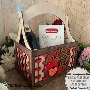 May include: A wooden gift basket with a handle, decorated with red hearts. The basket contains a bottle of sparkling wine, a box of confetti, and a sign that says "Happy Valentine's Day".