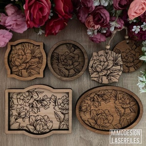 May include: Five wooden coasters with a floral design. The coasters are round, oval, and rectangular. The design features black floral patterns on a light brown background. The coasters are perfect for adding a touch of elegance to your home decor.