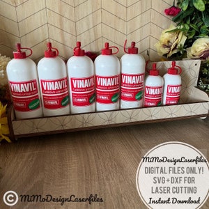 May include: A wooden shelf with seven white bottles of Vinavil adhesive. The bottles have red caps and labels with the brand name and the words "adesivo universal" in black. The shelf is made of wood and has a brown stain. The bottles are arranged in a row on the shelf.