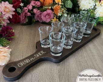 May include: A wooden shot glass holder with a handle. The holder has eight slots for shot glasses and the text "GRAB A SHOT..." is engraved on the handle. The holder is made of dark brown wood and has a natural wood finish.