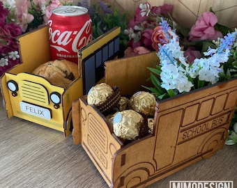 Op de afbeelding: Twee houten schoolbusvormige dozen. De gele doos heeft het woord "FELIX" op de voorkant en een blikje Coca-Cola erin. De bruine doos heeft de woorden "SCHOOL BUS" aan de zijkant en is gevuld met chocoladebonbons.
