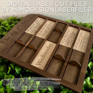 May include: A wooden laser-cut organizer with a dark brown finish. The organizer has slots for each day of the week, with labels for tasks like "Planning Week" and "Publish Video." The text "Digital Laser Cut Files" is at the top.