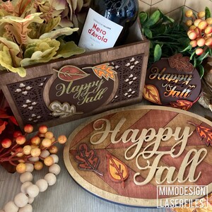May include: Two wooden signs featuring the text "Happy Fall" in gold lettering. The signs are adorned with autumn leaves in shades of red, orange, and brown. These signs are ideal for adding a touch of autumnal charm to your home decor.