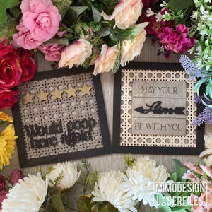 May include: Two wooden signs with black frames and a woven pattern. The first sign says "Would poop here again" with five gold stars. The second sign says "May your llama be with you".