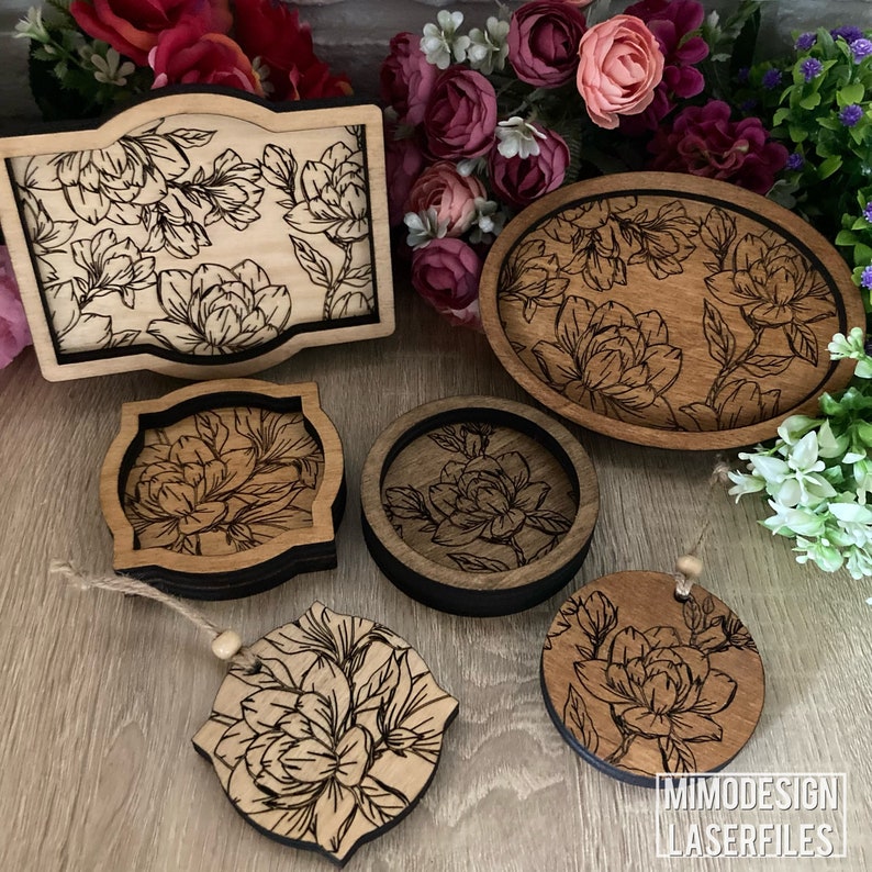 May include: A set of wooden coasters and a tray featuring a floral design. The coasters are round and square, and the tray is oval. All items are made of wood and have a dark brown stain. The floral design is engraved into the wood and features a delicate pattern of flowers and leaves.