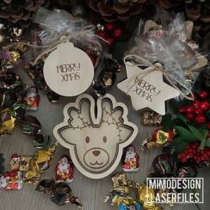 Può includere: Addobbi natalizi in legno con il testo "Merry Xmas" su di essi. Gli addobbi hanno la forma di una stella e di una palla di albero di Natale. Gli addobbi sono circondati da decorazioni natalizie rosse e verdi.