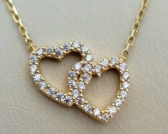 May include: A gold necklace with a double heart pendant. The hearts are outlined with small diamonds.