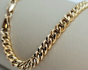 May include: A gold chain bracelet with a curb link design. The bracelet is made of thick, durable metal and has a polished finish.