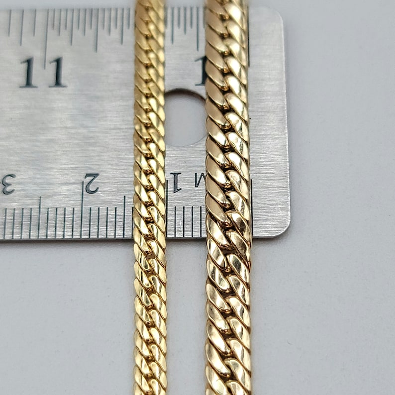 Op de afbeelding: Twee gouden kettingen van verschillende breedtes naast een liniaal. De kettingen zijn beide 11 inch lang.