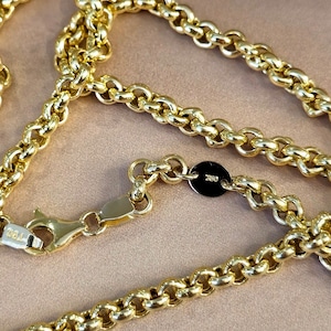 May include: A gold chain necklace with a lobster clasp and a small round tag with the inscription "750" on it.