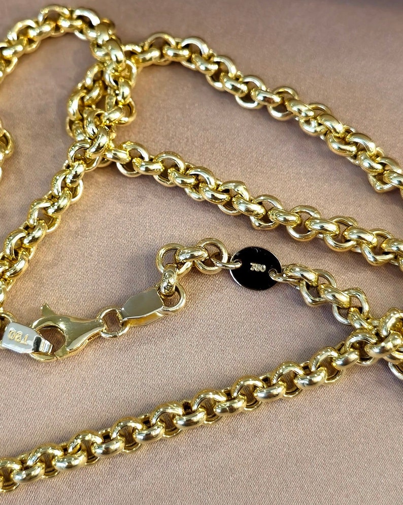 May include: A gold chain necklace with a lobster clasp and a small round tag with the inscription "750" on it.