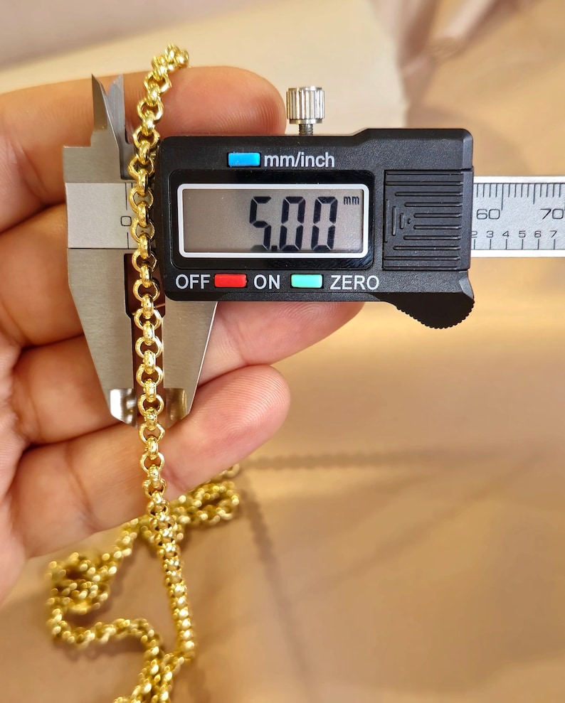 May include: Close-up of a gold chain measured with a digital caliper. The caliper reads 5.00 mm.