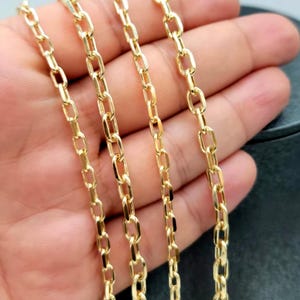 Puede incluir: Un collar de cadena de oro que presenta una serie de eslabones ovalados alargados y uniformes conectados en un patr&oacute;n continuo. El metal tiene una superficie pulida y reflectante que capta la luz, creando un aspecto amarillo met&aacute;lico.