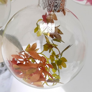 Foglie autunnali in miniatura di carta dipinta in una pallina di vetro