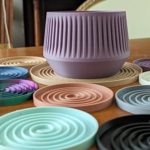 May include: A set of colorful coasters with a spiral design. The coasters are made of a soft, flexible material and are perfect for protecting your furniture from scratches and spills. The coasters are arranged in a circle around a purple planter.