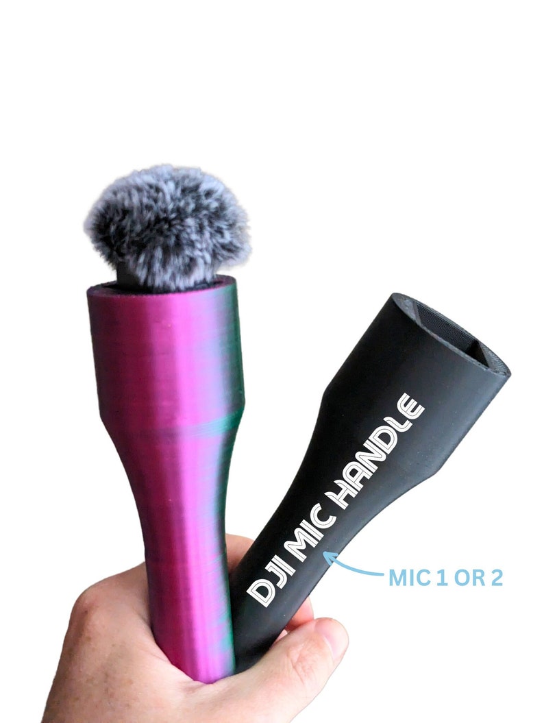 May include: Two microphone accessories are held in a hand. One is a purple and green microphone with a fuzzy gray windscreen. The other is a black handle with the text "DJI MIC HANDLE" and "MIC 1 OR 2".