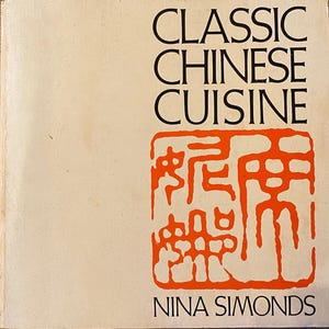 Può includere: Copertina di un libro con il titolo "CLASSIC CHINESE CUISINE" in nero. Sotto, un quadrato rosso con caratteri cinesi. Il nome dell'autore, NINA SIMONDS, è in basso.