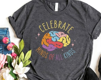 May include: A dark heather grey t-shirt with a colorful brain graphic and the text "Celebrate Minds of All Kinds".