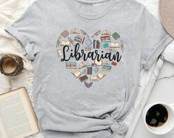 May include: A gray t-shirt with a heart-shaped design made of colorful books and the word "Librarian" in black text.