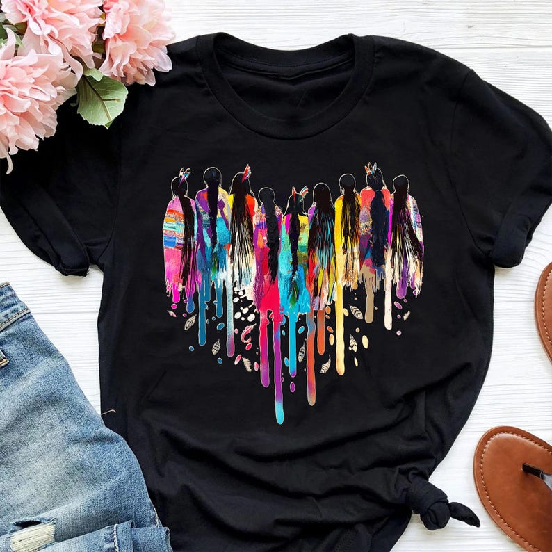 May include: Black t-shirt with a colorful heart design featuring a group of women with long hair. The heart is made of dripping paint in various colors, including red, orange, yellow, green, blue, and purple.
