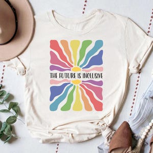 May include: A white t-shirt with a rainbow sunburst design and the text "The Future is Inclusive".