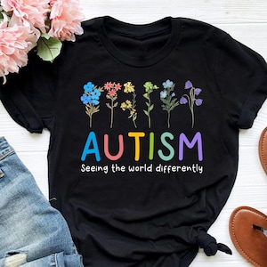 May include: Black t-shirt with a colorful flower design and the text "AUTISM Seeing the world differently".