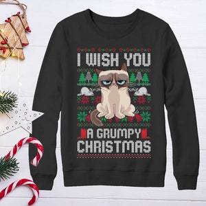 Peut inclure: Sweat-shirt noir à manches longues avec un motif de Noël représentant un chat grognon et le texte "Je vous souhaite un Noël grincheux".