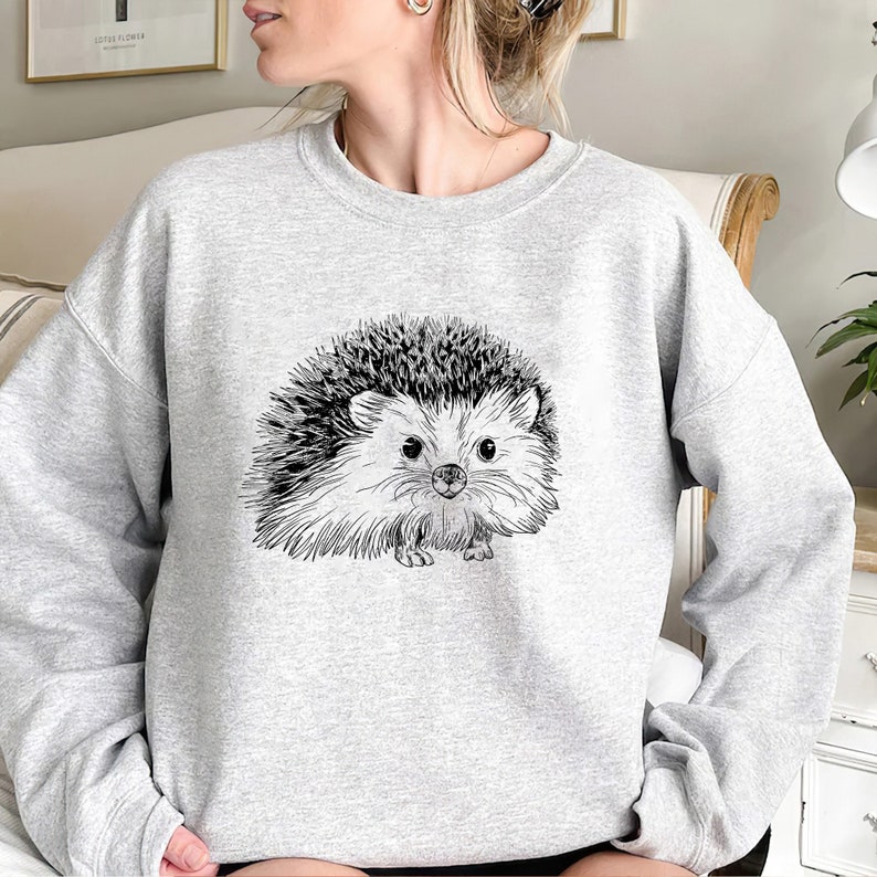 May include: A gray sweatshirt with a black and white line drawing of a hedgehog on the front.