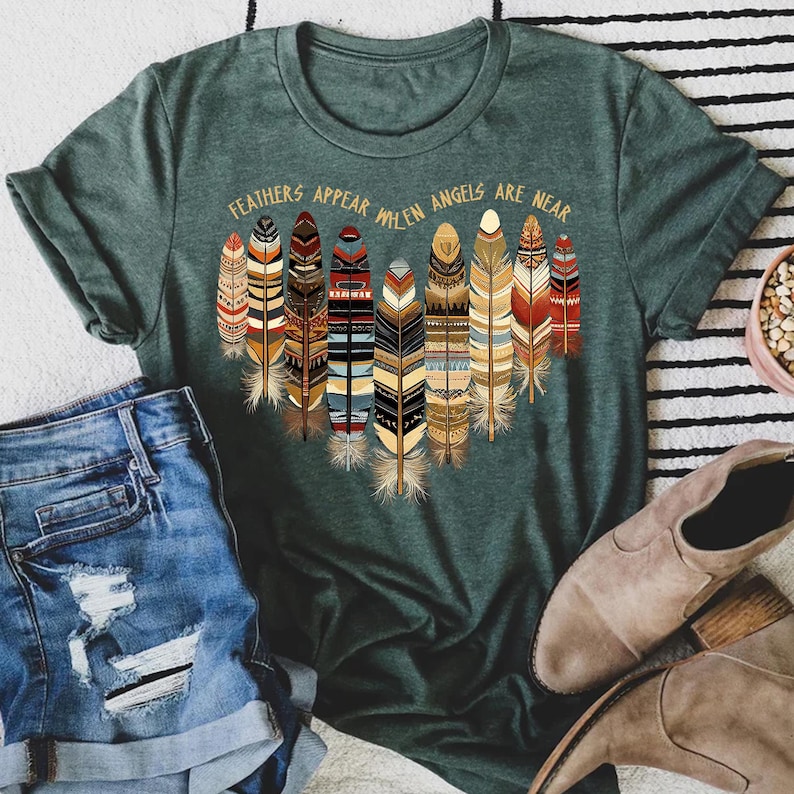 May include: Green t-shirt with a graphic of colorful feathers and the text "Feathers appear when angels are near".