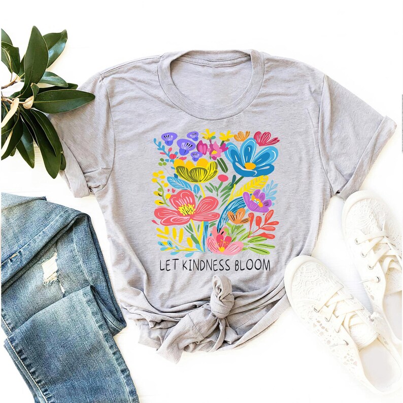 May include: A gray t-shirt with a colorful floral design and the text "Let Kindness Bloom".