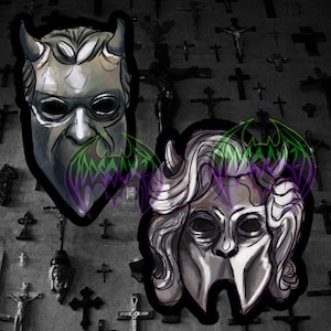 May include: Two black and white masks with a green and purple design. The masks are stylized and have a gothic aesthetic.