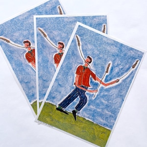 Puede incluir: Tres impresiones artísticas que presentan una ilustración caprichosa de una persona con camisa roja y pantalones a rayas azules, sosteniendo espigas de trigo. El fondo es un cielo azul con una colina verde y cubierta de hierba. La firma del artista está en la esquina inferior izquierda.