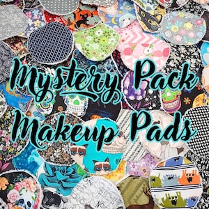 May include: A collection of colorful, patterned reusable makeup pads. The pads feature various designs, including floral, geometric, and novelty prints. The text "Mystery Pack Makeup Pads" is displayed in a teal font. The pads are round and appear to be made of fabric.