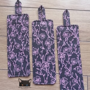 Peut inclure: Trois marque-pages en tissu noir avec un motif floral rose. Les marque-pages ont une boucle en haut pour une utilisation facile.