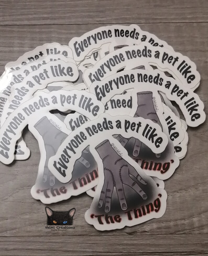 Peut inclure: Une pile d'autocollants blancs avec une illustration noire et grise d'une main avec le texte "Everyone needs a pet like The Thing" dessus.